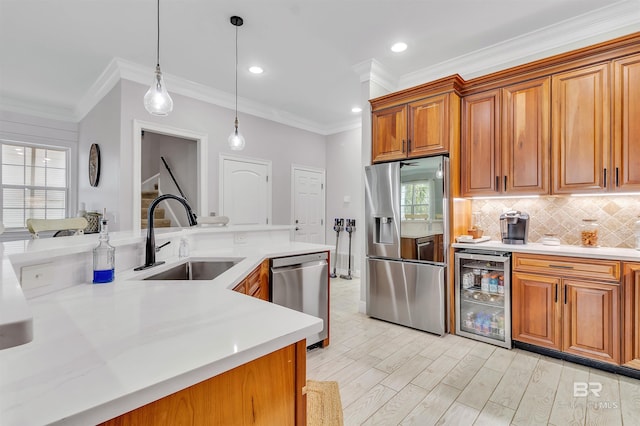 kitchen featuring beverage cooler, a sink, light countertops, appliances with stainless steel finishes, and brown cabinets