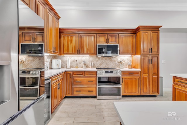 kitchen with stainless steel appliances, brown cabinetry, light countertops, and crown molding