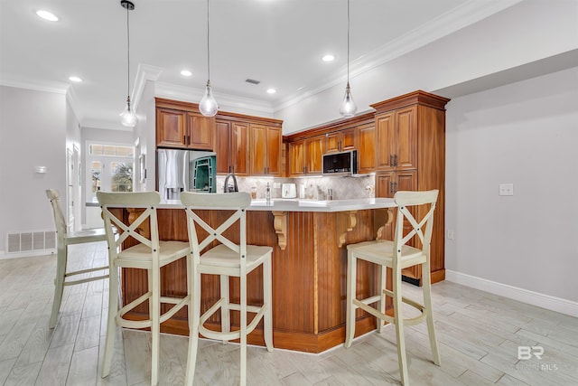 kitchen featuring appliances with stainless steel finishes, brown cabinetry, visible vents, and decorative backsplash