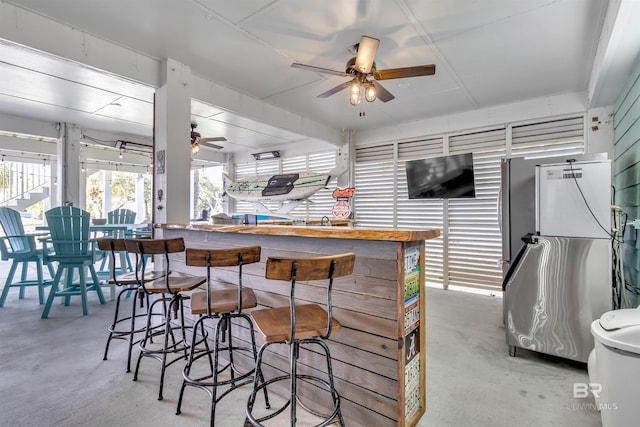 kitchen featuring concrete flooring, freestanding refrigerator, and a ceiling fan