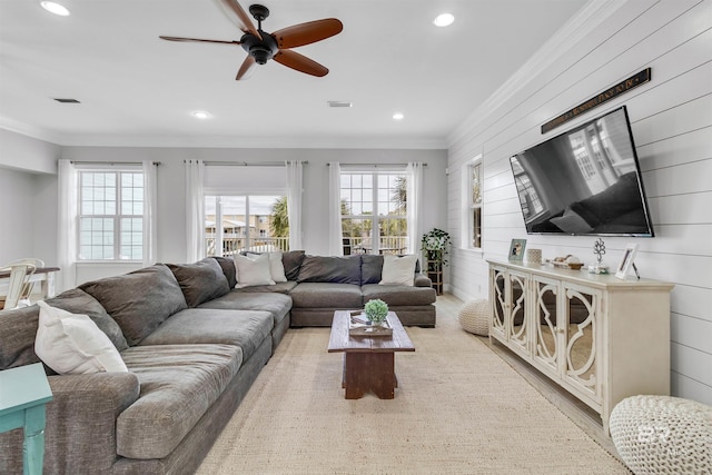 living room featuring wooden walls, visible vents, and crown molding