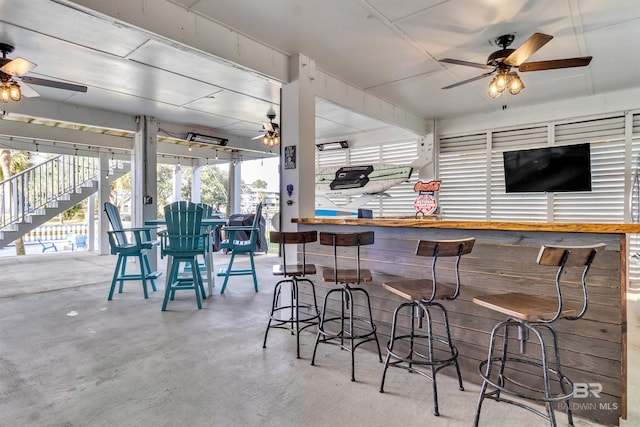 bar with ceiling fan and concrete flooring