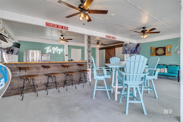 dining room featuring a bar, concrete floors, and wood walls