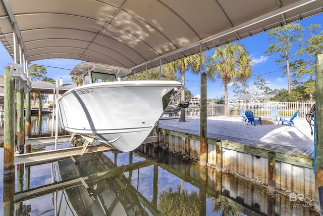 dock area featuring a water view, fence, and boat lift