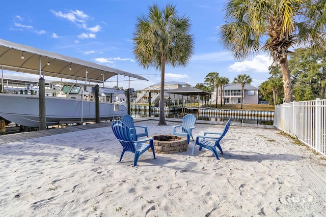 view of patio featuring an outdoor fire pit, a boat dock, boat lift, a residential view, and fence