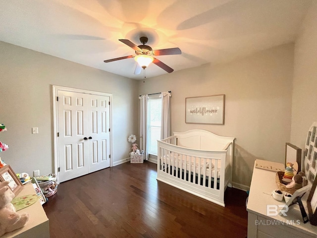 bedroom featuring a ceiling fan, a nursery area, wood finished floors, and baseboards