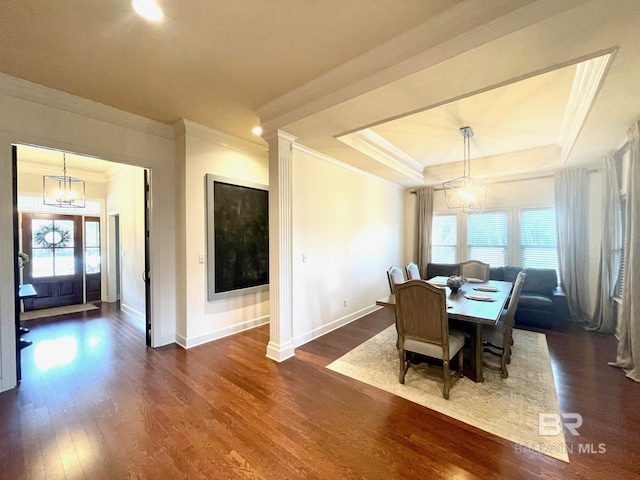 dining area with dark wood-type flooring, a notable chandelier, a healthy amount of sunlight, and a tray ceiling