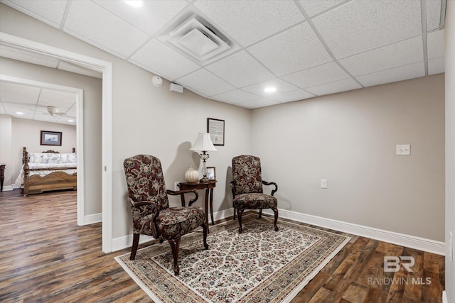 living area with dark hardwood / wood-style flooring and a drop ceiling