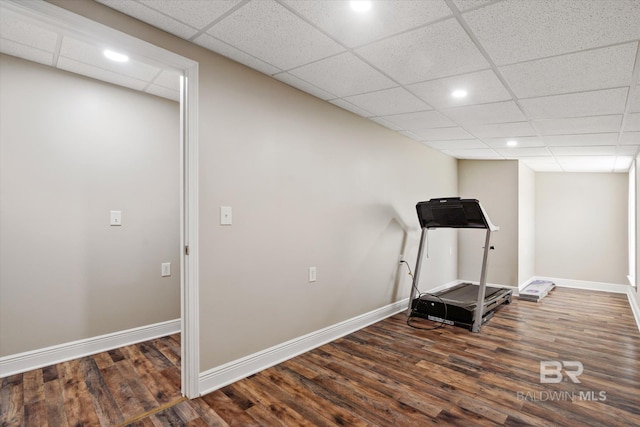 workout room featuring dark wood-type flooring and a drop ceiling