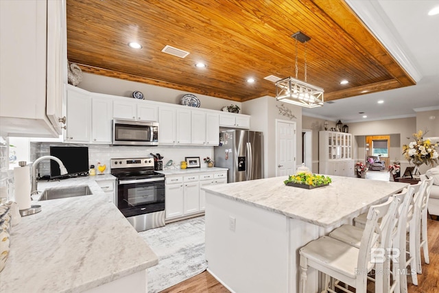 kitchen with appliances with stainless steel finishes, decorative light fixtures, sink, white cabinets, and wood ceiling