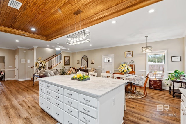 kitchen with pendant lighting, wood ceiling, a kitchen island, and white cabinets