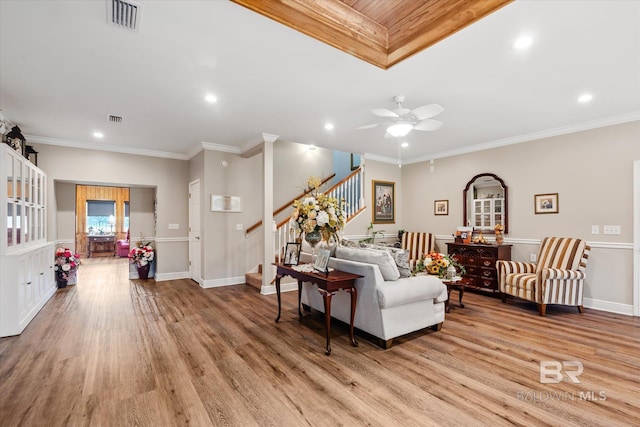 living room with ceiling fan, ornamental molding, and light wood-type flooring