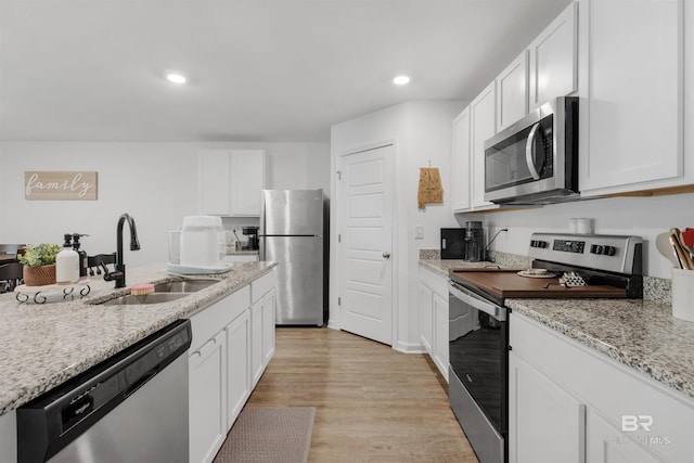 32299 Terranova Loop, Lillian, AL 36549 - kitchen featuring appliances with stainless steel finishes, a sink, white cabinets, light wood-type flooring, and recessed lighting
