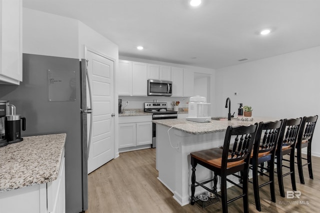 32299 Terranova Loop, Lillian, AL 36549 - kitchen featuring appliances with stainless steel finishes, light wood-style floors, white cabinetry, a sink, and recessed lighting