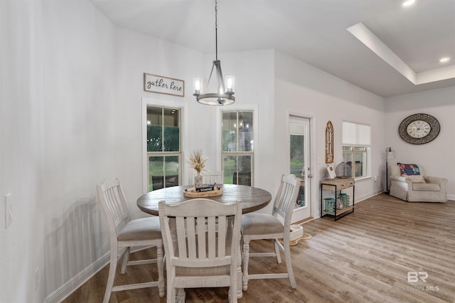 dining space featuring wood-type flooring and an inviting chandelier