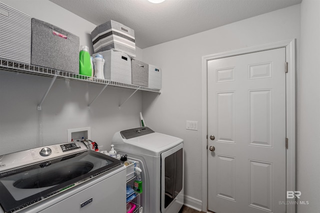 laundry area with independent washer and dryer and a textured ceiling