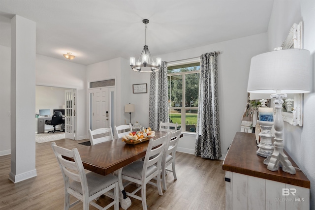 dining space with light hardwood / wood-style flooring and a chandelier