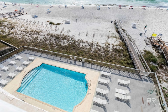 view of swimming pool with a patio area, a view of the beach, and a water view