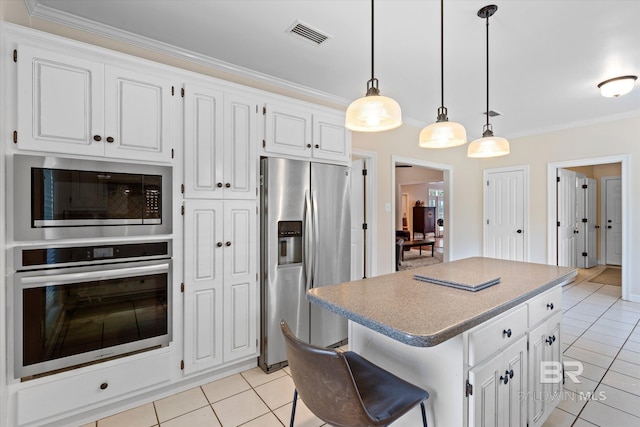 kitchen with appliances with stainless steel finishes, a center island, white cabinets, and decorative light fixtures