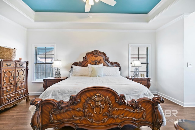 bedroom featuring hardwood / wood-style flooring, ornamental molding, a tray ceiling, and ceiling fan