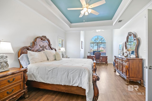 bedroom featuring ceiling fan, hardwood / wood-style floors, a raised ceiling, and ornamental molding