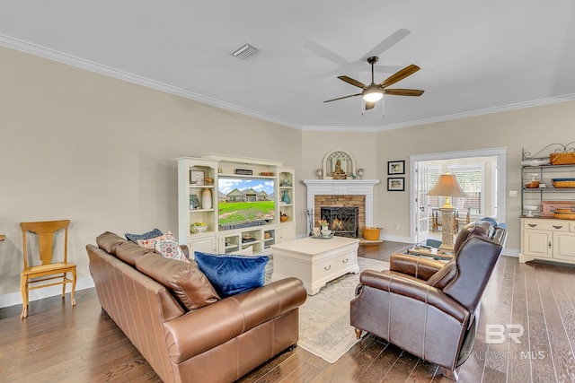 living room featuring ceiling fan, ornamental molding, a fireplace, and dark hardwood / wood-style flooring