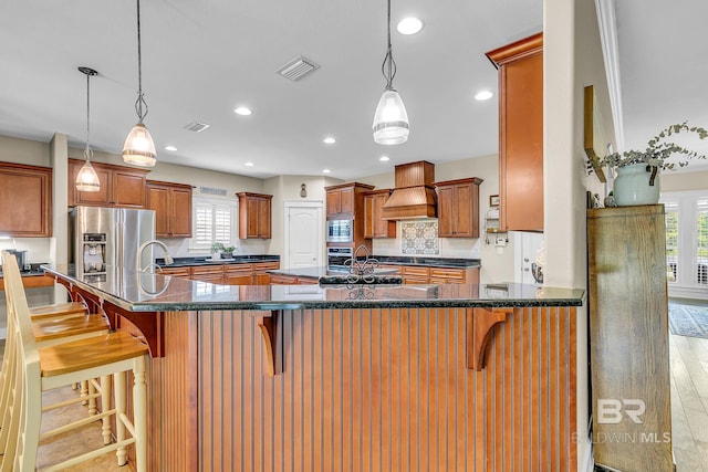 kitchen featuring a kitchen breakfast bar, kitchen peninsula, stainless steel appliances, and a healthy amount of sunlight