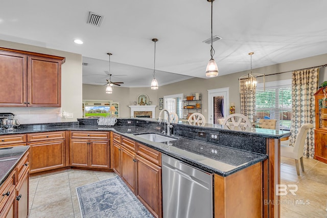 kitchen with dishwasher, decorative light fixtures, sink, light tile patterned floors, and dark stone countertops