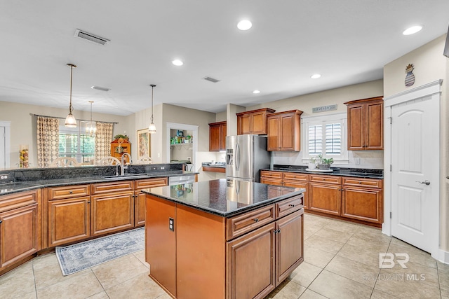 kitchen with hanging light fixtures, appliances with stainless steel finishes, sink, light tile patterned floors, and a kitchen island