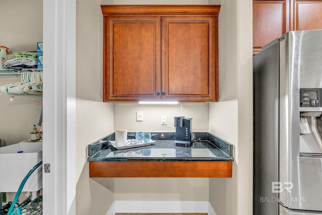 kitchen featuring sink, dark stone counters, and stainless steel refrigerator with ice dispenser