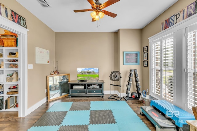 exercise area with ceiling fan and dark hardwood / wood-style flooring