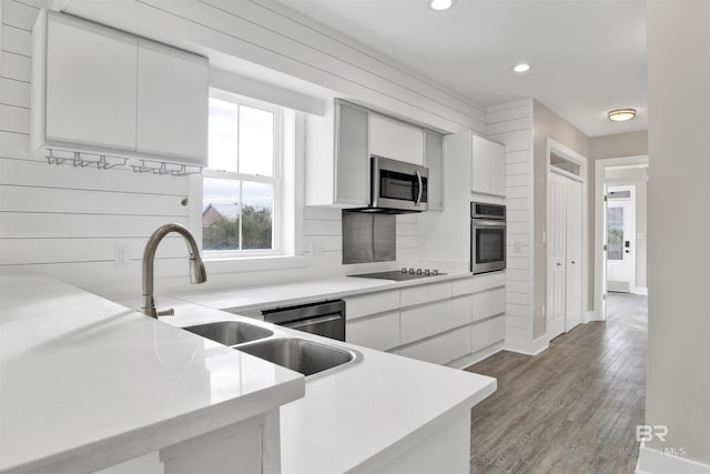 kitchen with light wood-type flooring, appliances with stainless steel finishes, sink, and white cabinetry