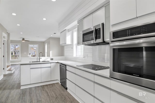 kitchen with white cabinets, kitchen peninsula, appliances with stainless steel finishes, and sink