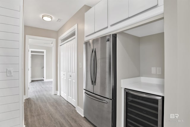 kitchen featuring light hardwood / wood-style floors, white cabinetry, stainless steel fridge, and wine cooler