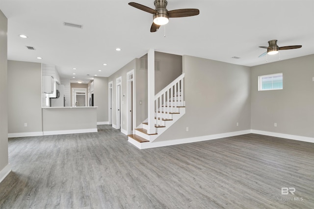 unfurnished living room featuring ceiling fan and hardwood / wood-style floors