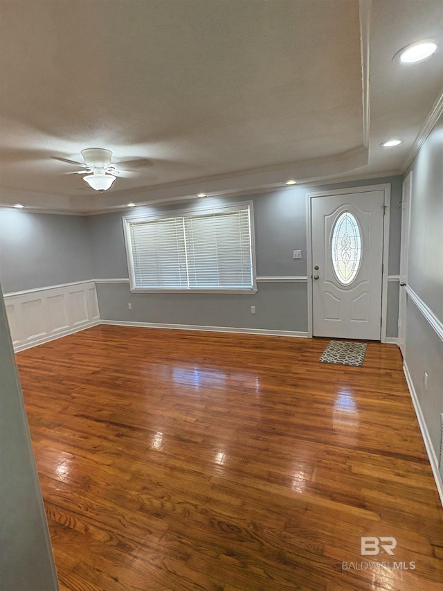 foyer entrance featuring wood-type flooring, ornamental molding, and ceiling fan