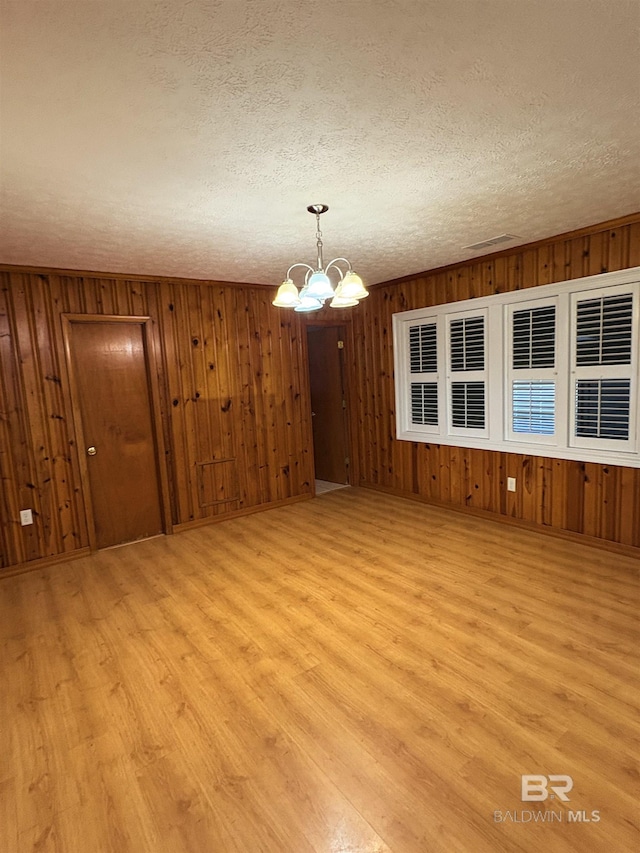 interior space with an inviting chandelier, light hardwood / wood-style floors, and a textured ceiling