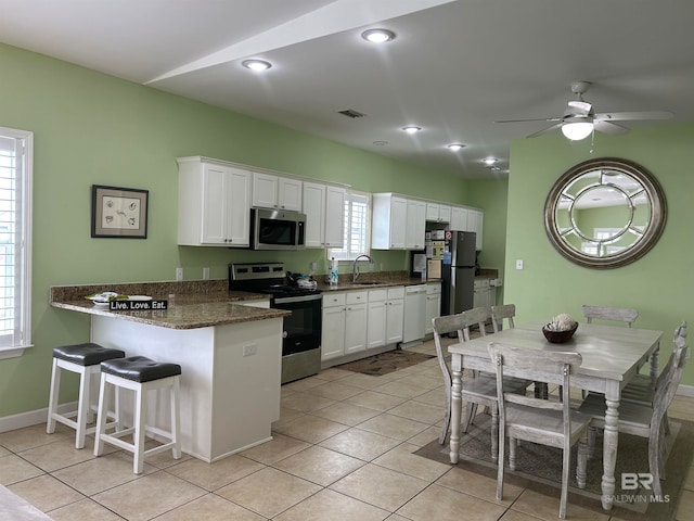 kitchen featuring kitchen peninsula, white cabinetry, stainless steel appliances, and plenty of natural light