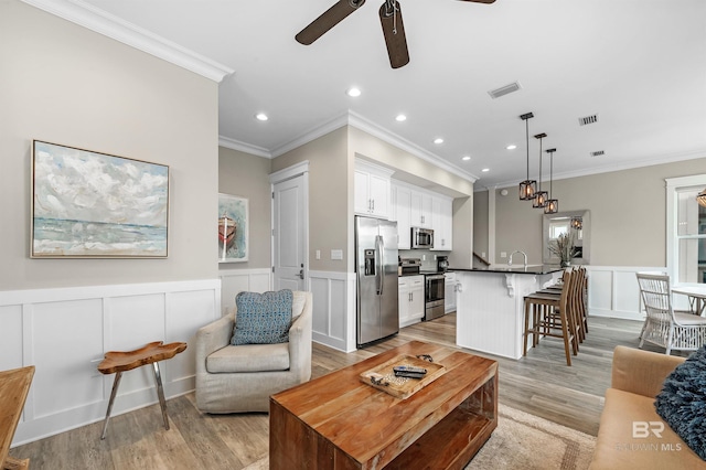 living room with recessed lighting, wainscoting, visible vents, and light wood finished floors