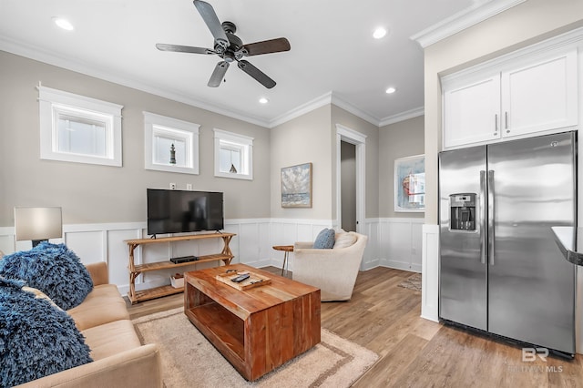 living area with crown molding, recessed lighting, light wood-style floors, wainscoting, and ceiling fan