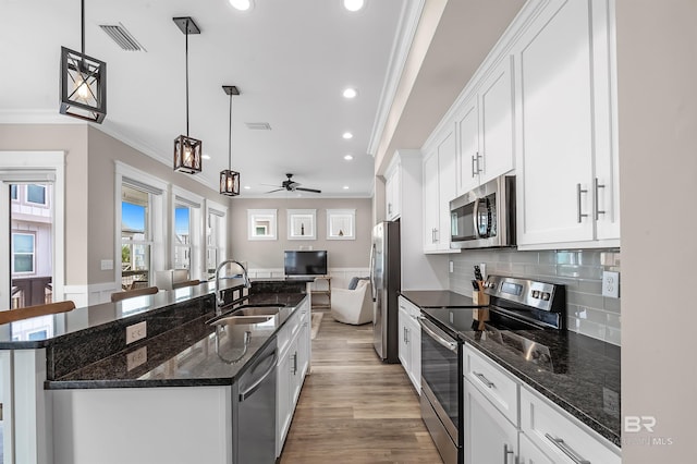 kitchen featuring stainless steel appliances, hanging light fixtures, a sink, and a kitchen island with sink