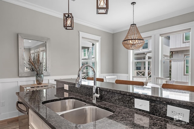 kitchen with crown molding, pendant lighting, a sink, and dark stone countertops