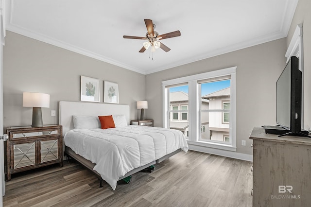 bedroom featuring a ceiling fan, baseboards, ornamental molding, and wood finished floors