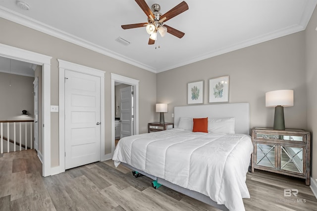 bedroom with crown molding, light wood-style flooring, visible vents, and attic access