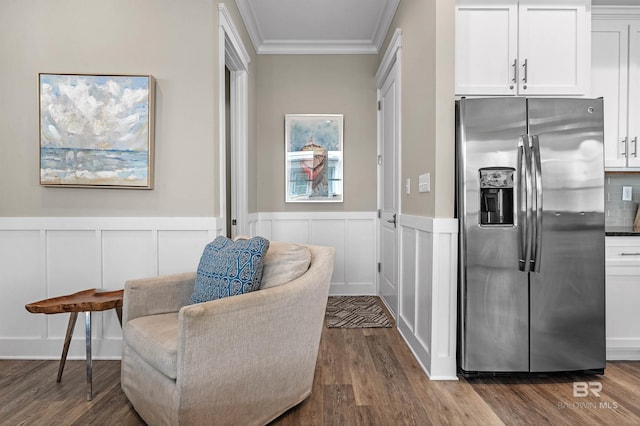 living area with dark wood-style floors, wainscoting, crown molding, and a decorative wall