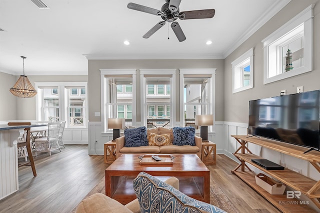 living room with recessed lighting, wainscoting, crown molding, and wood finished floors