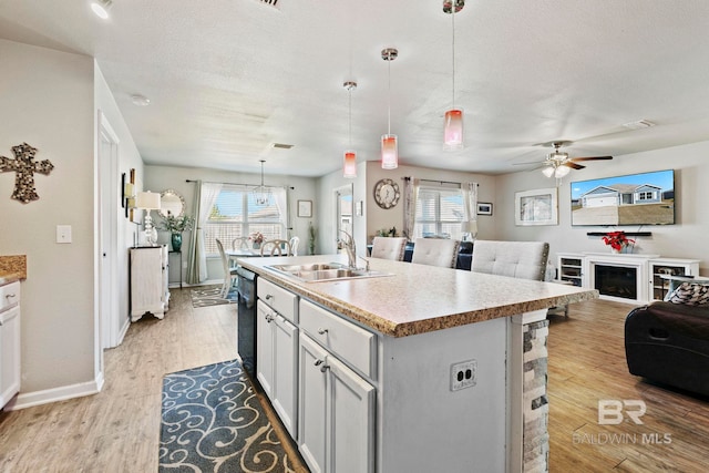 kitchen featuring a center island with sink, light hardwood / wood-style floors, decorative light fixtures, and sink