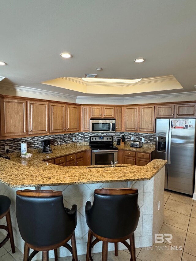 23450 Perdido Beach Blvd Unit 2710, Orange Beach, AL 36561 - kitchen with appliances with stainless steel finishes, a tray ceiling, crown molding, brown cabinetry, and recessed lighting