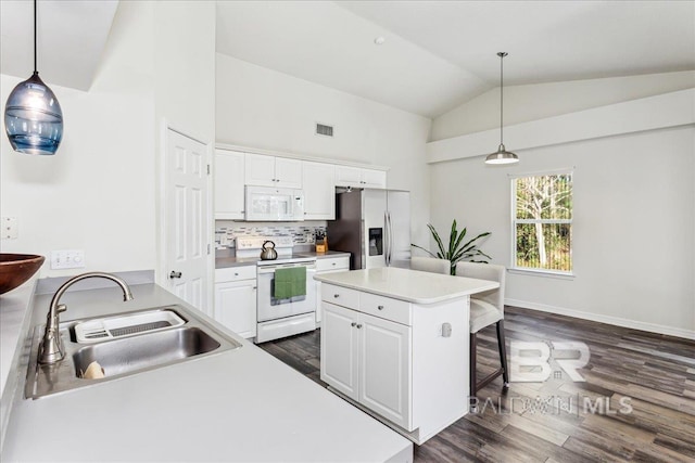 kitchen featuring visible vents, white cabinetry, a sink, white appliances, and a kitchen breakfast bar