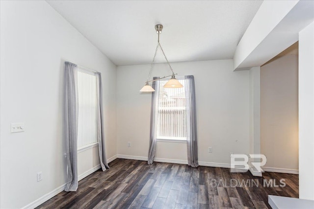 unfurnished dining area with dark wood finished floors and baseboards